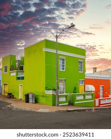 Buildings on a corner, with a dramatic sunset sky in the background, showcasing architectural beauty and vibrant hues in the cultural meca of Bo-Kaap South Africa located in Cape Town.