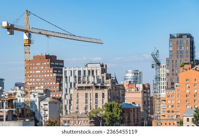 Built space of real estate developer. Industrial construction cranes work above new modern building. Engineering multistory design from concrete block and overlap. Development high-rise apartment.