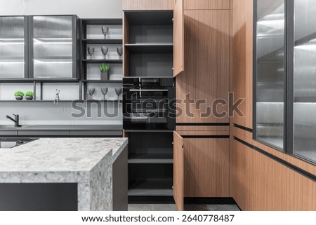 built-in kitchen with upper and lower cabinets. facades are wooden, gray and glass. Built-in kitchen appliances. kitchen unit with lots of cupboards and shelves. Some drawers and cupboards are open.