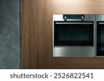 A built-in microwave oven with a digital display, seamlessly integrated into a light wooden kitchen cabinet. Built-in microwave oven close-up in the kitchen