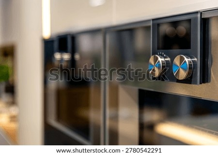 Built-in oven details with metallic knobs. Modern kitchen appliances in interior.