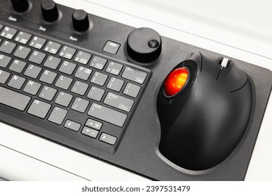 Built-in tabletop input device, black industrial keyboard with red trackball mouse, modern navigation equipment mounted on a control panel at captains bridge 