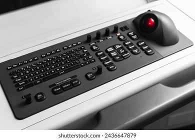 Built-in tabletop input device, black industrial keyboard with a trackball mouse, modern navigation equipment mounted on a control panel at captains bridge. Marine navigation simulation system