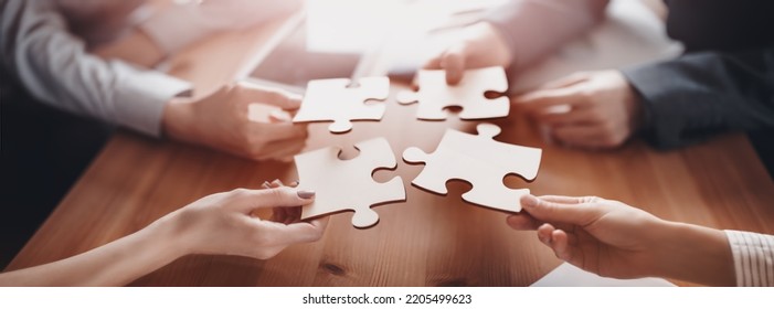 Buisnesswomen and buisnessmen working together while putting together puzzles. Concept of teamwork and cooperation in business - Shutterstock ID 2205499623