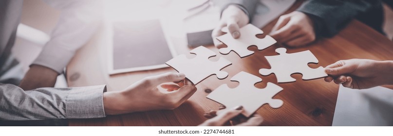 Buisnesswomen and buisnessmen working together while putting together puzzles. - Powered by Shutterstock