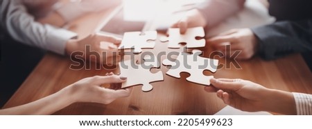Buisnesswomen and buisnessmen working together while putting together puzzles. Concept of teamwork and cooperation in business