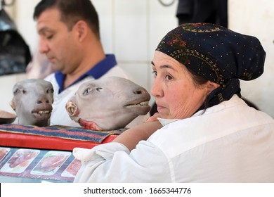 Bukhara, Uzbekistan - April, 2019: People Of The Country. Saleswoman In Front Of Sheep Head. Food Market (bazaar).