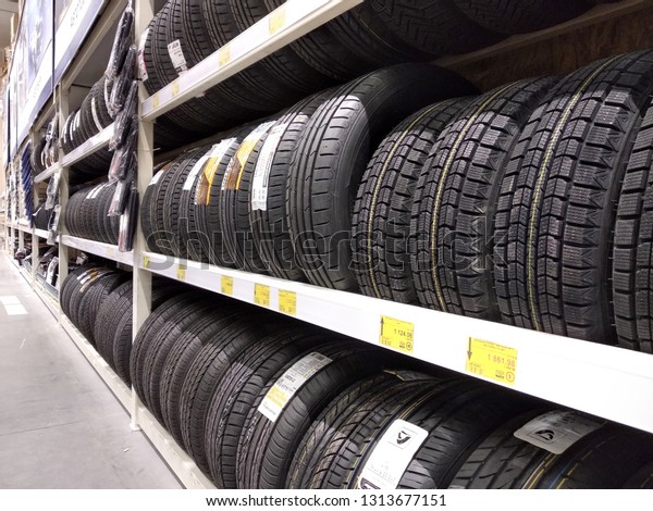 Bukovel, Ukraine - November 25,\
2018: Long row of stack new black rubber car wheel tires in auto\
shop. Vehicle accessories, transport business and safe driving\
concept.