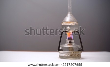 Bulb with boiling liquid on burner flame. Flask heated on burner in laboratory