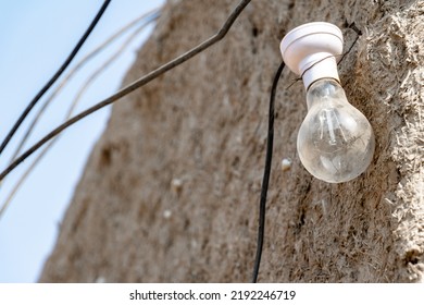 A Bulb Without Electricity Is Hanging On A Muddy Wall In The Village