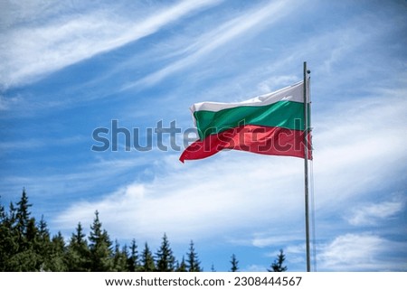 Bulgarian national flag on a pole against silky clouds.