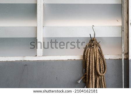 Bulk of long rope which is hanging on the warehouse wall, prepared to use as tagline to secure the object during lifting. Industrial equipment object photo. 