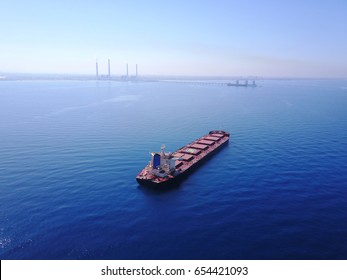 a bulk ship outside the port on a bog power station and its dock background