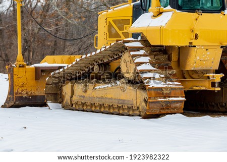 Bulldozer at construction site after winter snow storm. Concept of construction industry, work delay and stoppage.