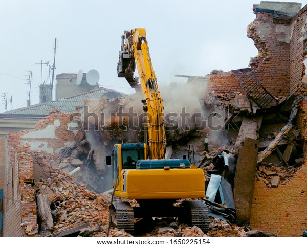 A bulldozer destroys an old building. The concept
of the demolition of a building under construction of a new house.
Dismantling an old house