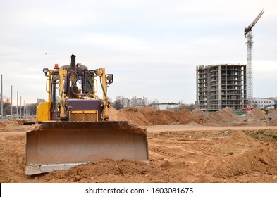 Bulldozer During Of Large Construction Jobs At Building Site. Land Clearing, Grading, Pool Excavation, Utility Trenching And Foundation Digging. Crawler Tractor,  Dozer, Earth-moving Equipment.