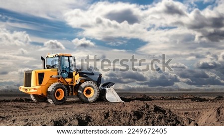 Bulldozer or loader at a construction site shovels mountain soil into a heap. Powerful wheel loader or bulldozer with a large bucket at a construction site. Construction equipment for earthworks