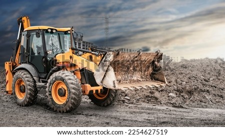 Bulldozer or loader at a construction site shovels mountain soil into a heap. Powerful wheel loader or bulldozer with a large bucket at a construction site. Construction equipment for earthworks