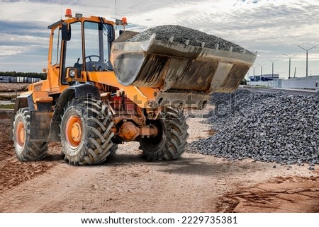Bulldozer or loader at the construction site transports gravel or crushed stone. Construction equipment for earthworks. Moving bulk building materials