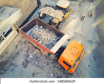 Bulldozer loader uploading waste and debris into dump truck at construction site. building dismantling and construction waste disposal service. Aerial drone industrial background