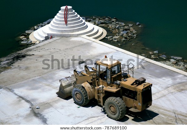 A bulldozer in making a concrete pier in the\
harbor of Mykonos, Greece
