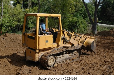 Bulldozer Moving Dirt With Trees In The Background