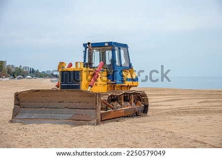 Bulldozer on the sandy beach. Heavy equipment for leveling the landscape.