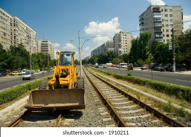 Bulldozer on tram tracks in plain day.