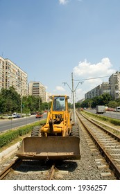 Bulldozer on tram tracks in plain day.