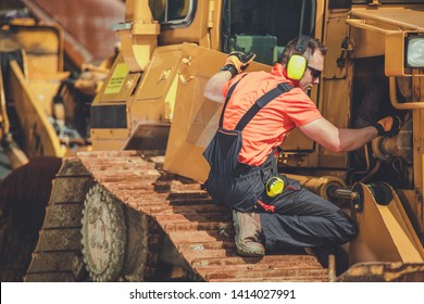 Bulldozer Professional Mechanic. Caucasian Technician Taking Machine Under Maintenance. Construction Heavy Duty Equipment.