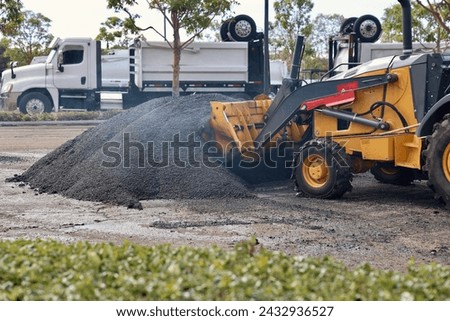 Bulldozer scooping up hot asphalt on the construction site
