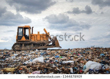 bulldozer working on landfill with birds in the sky