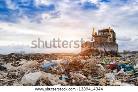 bulldozer working on landfill with birds in the sky. Sunset