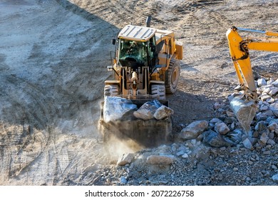 Bulldozer is working in site. A bulldozer or dozer is a large, motorized machine that travels on continuous tracks or large tires and is equipped with a metal blade to the front for pushing material.