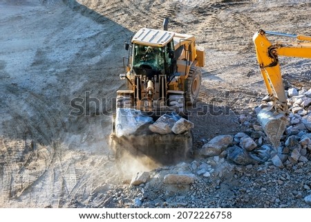 Bulldozer is working in site. A bulldozer or dozer is a large, motorized machine that travels on continuous tracks or large tires and is equipped with a metal blade to the front for pushing material.