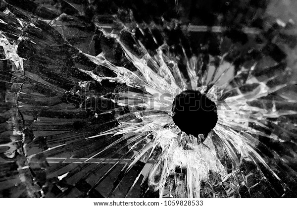 A bullet hole in the car\'s glass, close-up.\
Black and white background 