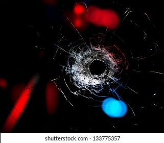 Bullet hole in the glass on  black background.