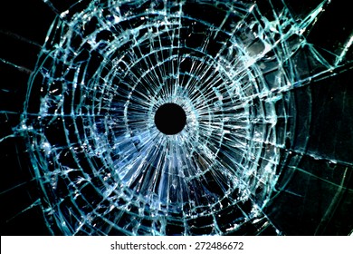 Bullet hole in a shattered piece of glass                               