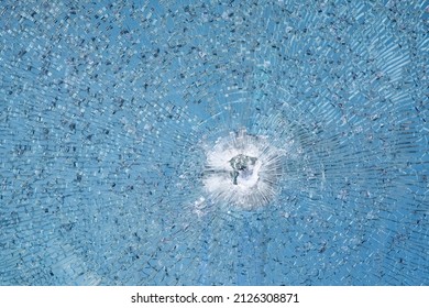 Bullet Hole In Window. Cracked Tempered Glass With Cracks Pattern. Vandalism, Destruction Concept. Broken Glass Due To Crime, Robbery Of Shop Concept.