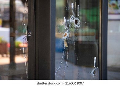 Bullet Holes On The Window Of Local Restaurant, Shot During War Shooting. Cracks Spreading Around Holes. Forensics Investigation Marks And Traces On The Glass.