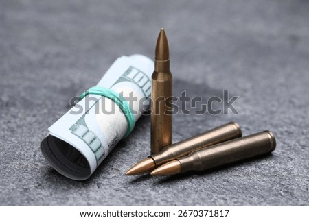 Bullets and dollars on grey table, closeup