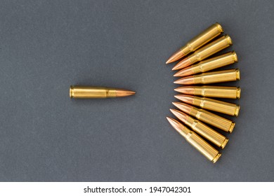Bullets on gray paper background, one bullet in front of the others. Cartridges 7.62 caliber for Kalashnikov assault rifle. One against all concept