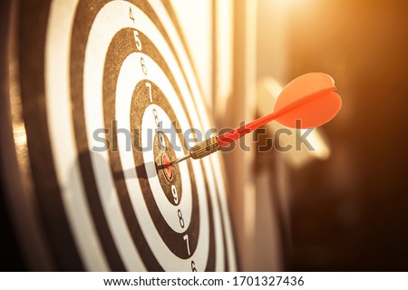 Bullseye(bull's-eye) or dart board has dart arrow hitting the center of a shooting target for business targeting and and  marketing goal concetps.