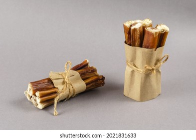 Bully sticks for dogs wrapped in brown paper and tied with twine. Portioned grouped Beef pizzle for pets. Popular Chewing treats on gray background. Air-dried 6-Inch Regular Bully Sticks