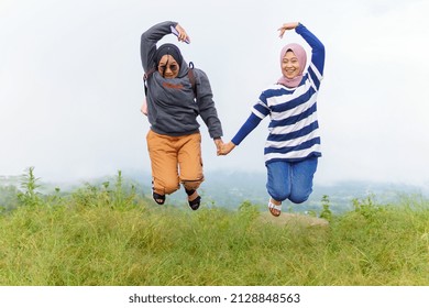 Bulukumba, Indonesia -january 20 2022 :happy women traveling and jumping together in mountains. at the peak of ma ra sinjai