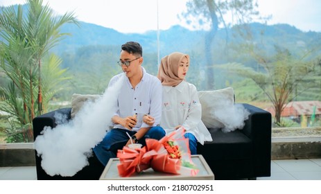 Bumijawa , Indonesia - May 22 , 2022
couple taking intimate photos in cafe and smoking vape