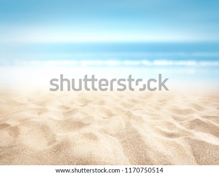 Bumpy tropical sandy beach with blurry blue ocean and sky
