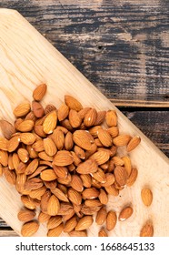 Bunch Of Almond On A Wooden Board On A Dark Wooden And Black Background. Top View.