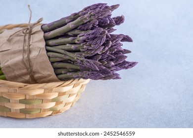 Bunch of asparagus Pacific Purple. Fresh spring vegetable in basket. Copy space background - Powered by Shutterstock