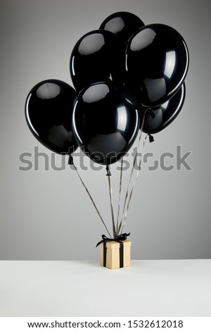 bunch of black balloons with gift box isolated on grey, black Friday concept